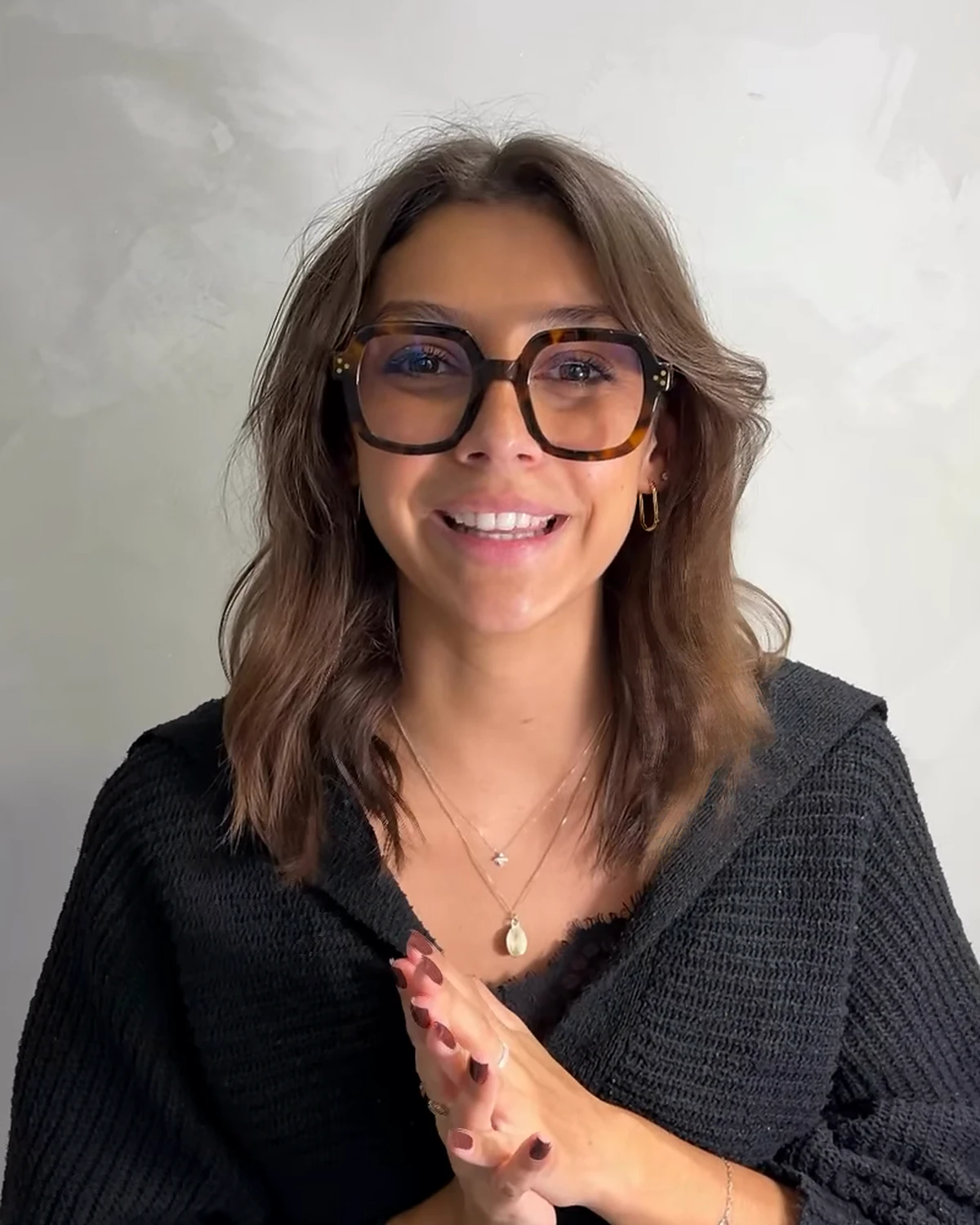 Juliette Santa Cruz, souriante, lunettes et pull noir